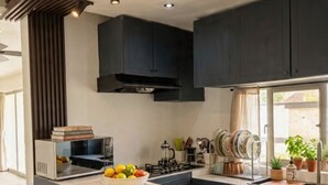 A modern kitchen with dark cabinetry, a marble island, and a built-in stove. - Marvelous 3-bedroom house with AC in charming in Bani, Pizarrete (Pizarrete)