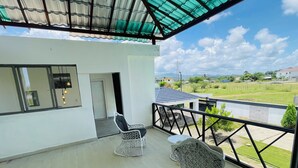 A balcony with two wicker chairs, a table, and a view of a green landscape. - Marvelous 3-bedroom house with AC in charming in Bani, Pizarrete (Pizarrete)