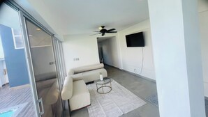 A modern living room with a sofa, a glass coffee table, a ceiling fan, and a flat-screen TV mounted on the wall. - Marvelous 3-bedroom house with AC in charming in Bani, Pizarrete (Pizarrete)