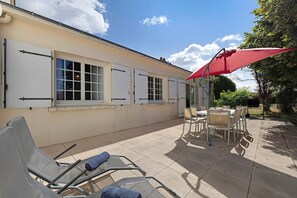 Un bâtiment doté d’un patio avec des espaces de détente en plein air et un parasol rouge.