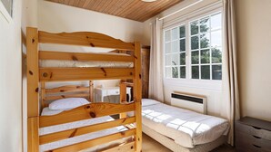 Una camera da letto con un letto a castello, un letto singolo, una scrivania e una finestra con tende.