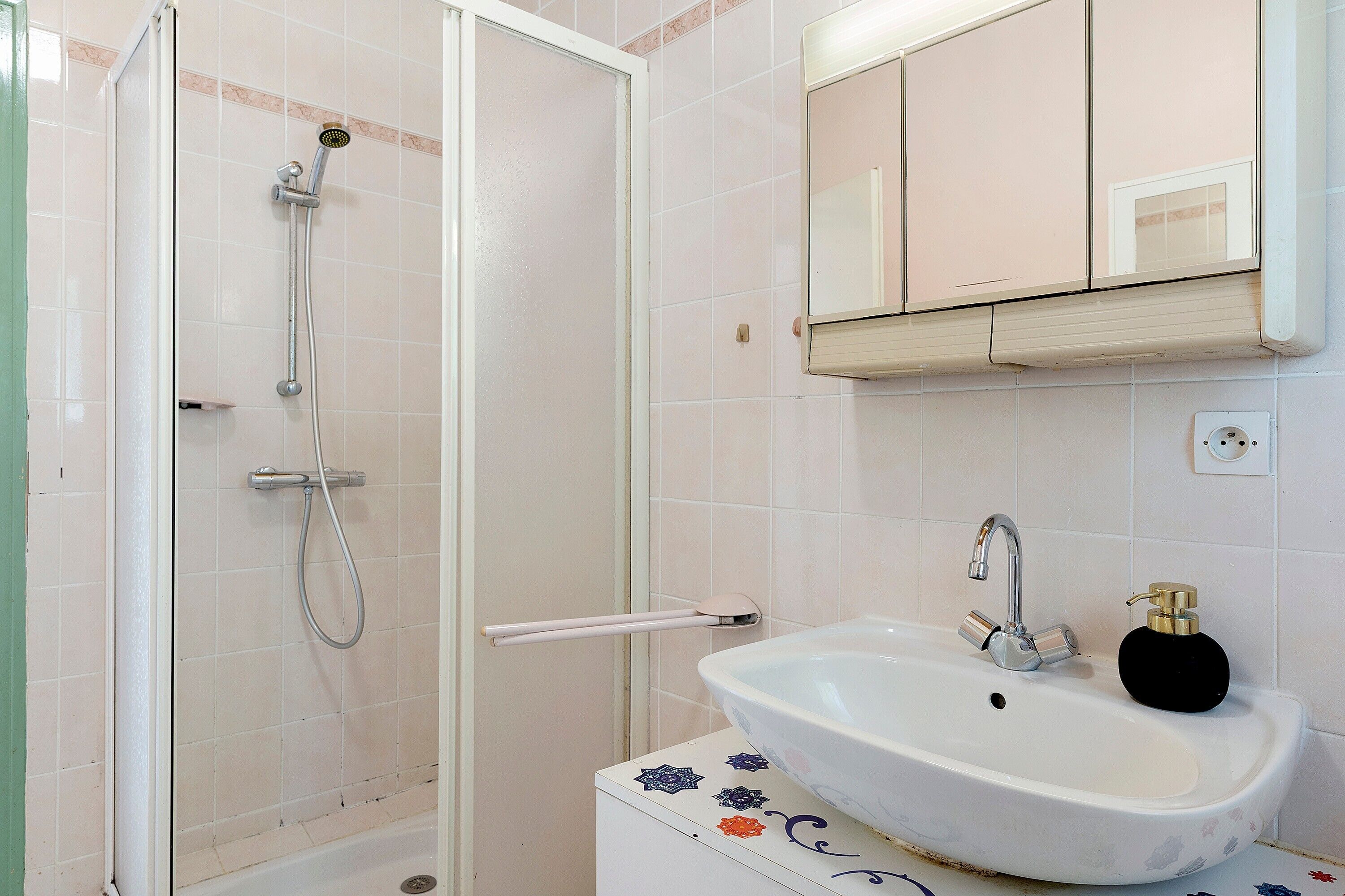 A bathroom with a shower, sink, mirror, and decorative tiles.. One Hectare Near the Ocean