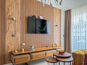 Ein modernes Wohnzimmer mit Holzvertäfelung, einem Flachbildfernseher, einem Holztischelement und einem runden Couchtisch.