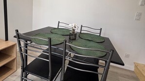 A dining area with a table, chairs, a clock, and a vase with flowers. - Mimi's House (Maubert-Fontaine)