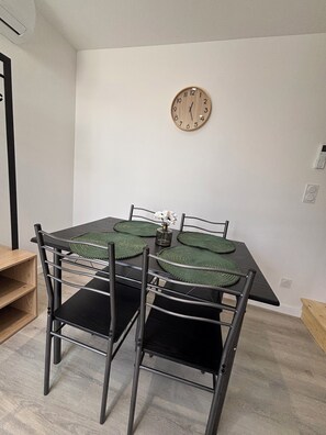 Een eetruimte met een tafel, stoelen, een klok en een vaas met bloemen.