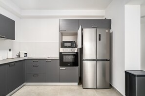 A modern kitchen with a built-in microwave, oven, and stainless steel refrigerator. - Modern 4BR Balcony Mamad Renovated Bldg (Bat Yam)