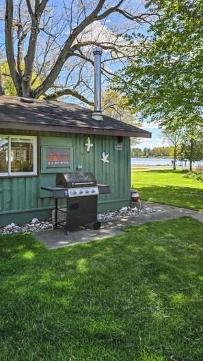 Una estación de parrilla al aire libre con chimenea, un letrero que dice 'LOVE SANFORD' y vista a un lago.