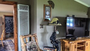 A living room with a wooden rocking chair, a television, and a patterned rug. - Bell Inn Cottage (Sanford)
