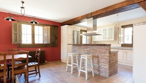 A kitchen with a brick island, wooden chairs, and a dining table.