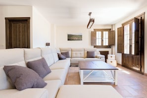 A living room with a sectional sofa, a coffee table, and a painting on the wall.