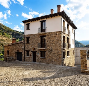A stone building with a flat roof, multiple balconies, and a cobblestone courtyard.
