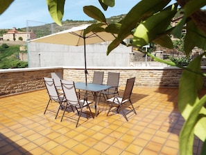 A patio with a table and chairs, a large umbrella, and a stone wall.