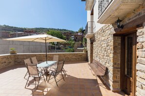 A patio with a table and chairs, a wooden bench, and a stone wall.