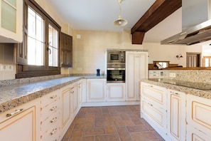 A kitchen with white cabinetry, a granite countertop, a stainless steel oven, and a built-in microwave.