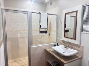 A bathroom with a shower, a sink, and a mirror.