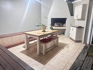 Eine Küche mit integriertem Grill, einem Holztisch mit Kissen und einem Blumentopf.
