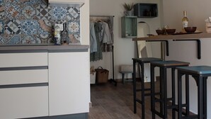 A modern kitchen with a tiled backsplash, a bar area with stools, and a hanging plant. - ByVigin Azalea – Elegance, Relaxation, and a Private Outdoor Jacuzzi (Magliano Alfieri)