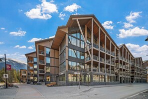 A multi-story building with balconies, large windows, and a mountainous backdrop. - Timberstone Modern Gem - Timberstone (Canmore)