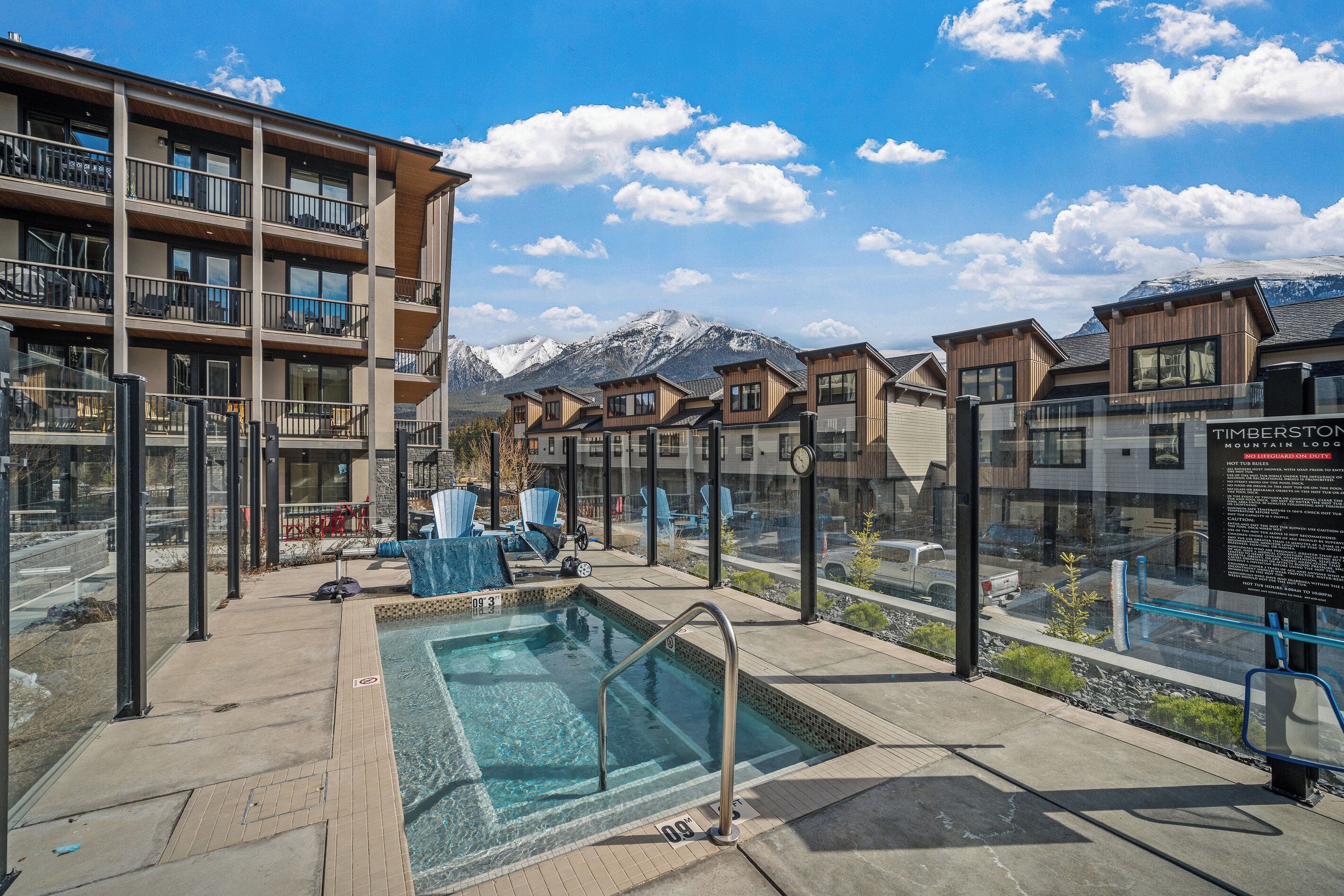 A pool area with a view of mountains, a covered seating area, and a signboard.