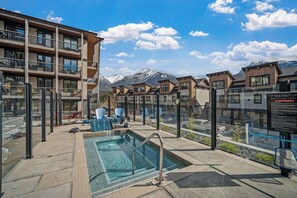 A pool area with a view of mountains, a covered seating area, and a signboard. - Timberstone Modern Gem - Timberstone (Canmore)