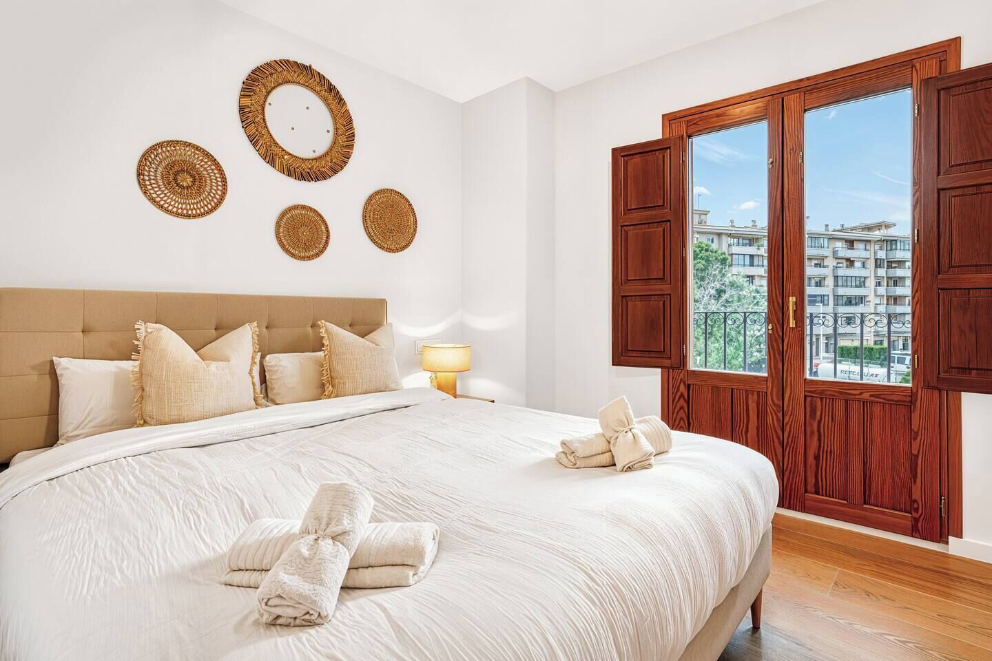 Een slaapkamer met een groot bed, een houten hoofdbord, een raam met houten luiken en wanddecoratie.