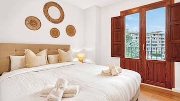 Een slaapkamer met een groot bed, een houten hoofdbord, een raam met houten luiken en wanddecoratie.