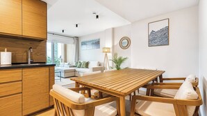 Una cucina moderna con mobili in legno, un tavolo da pranzo con sedie e un angolo salotto con divano e lampada.