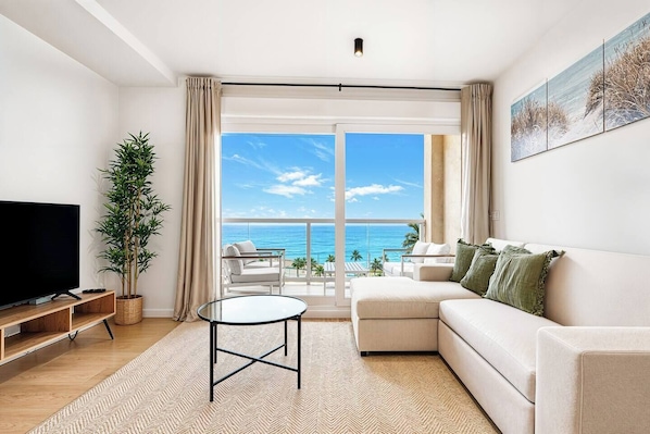 A modern living room with a television, a potted plant, a sofa, and a balcony with a view of the ocean. - Sea View Apartment with Terrace - Horizon (La Vila Joiosa)