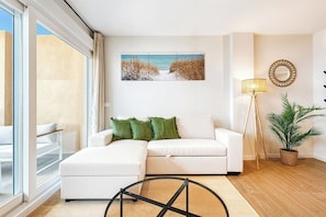 A modern living room with a white sofa, a floor lamp, a potted plant, and a painting of a beach scene. - Sea View Apartment with Terrace - Horizon (La Vila Joiosa)