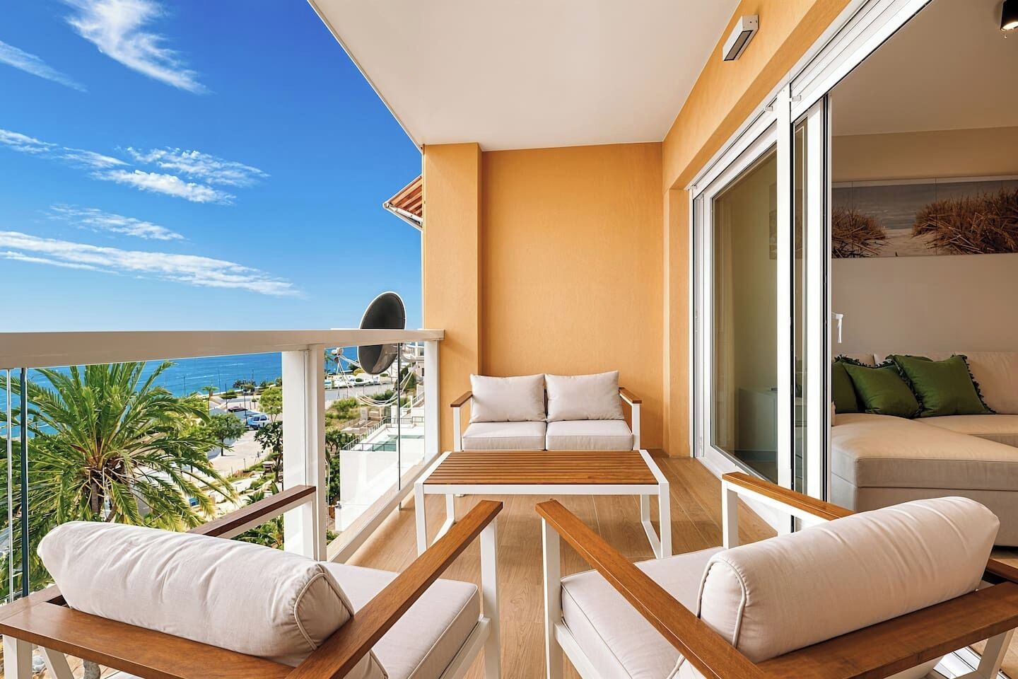 Een balkon met een bank, een tafel en een stoel, met uitzicht op de kust.