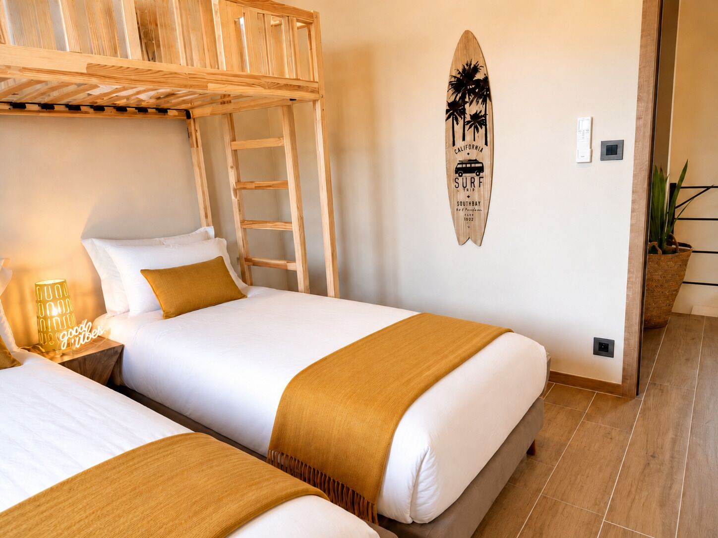 A room with two beds, a ladder, a surfboard decoration, and a plant.