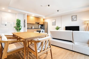 A modern living space with a wooden dining table, white sofa, and kitchen area. - Sea View Apartment with Terrace - Sunlight (La Vila Joiosa)