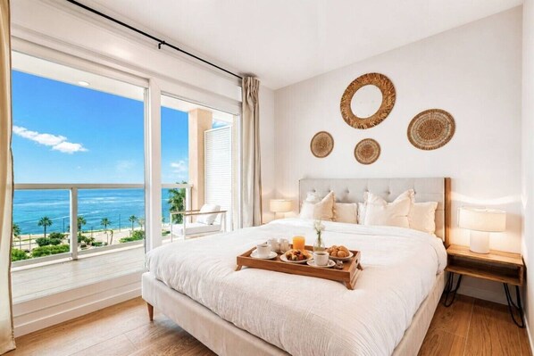 A bedroom with a large bed, a bedside table, a tray with breakfast items, and a view of the ocean. - Sea View Apartment with Terrace - Sunlight (La Vila Joiosa)