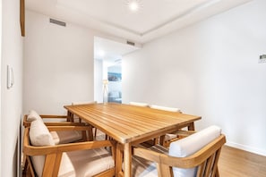 A dining area with a wooden table and cushioned chairs, a visible air vent, and a view into another room. - Sea View Apartment with Terrace - Sunset (La Vila Joiosa)