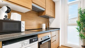 Une cuisine moderne avec des meubles en bois, un four à micro-ondes, un lave-linge et une grande fenêtre.