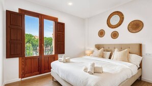 Une chambre avec un grand lit, des volets en bois et une vue sur la verdure.