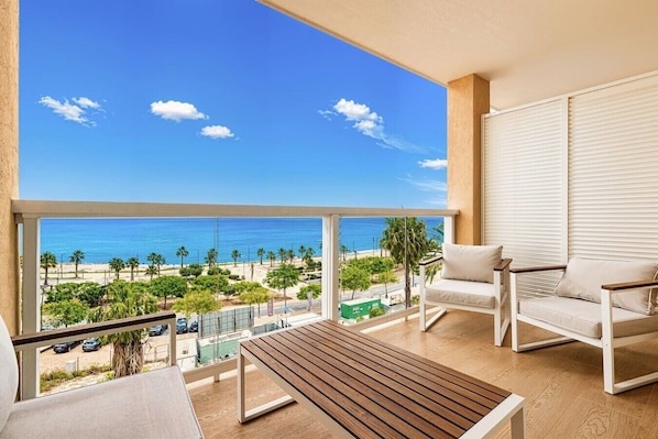 A balcony with a view of the beach, a wooden table, and two white chairs. - Sea View Apartment with Terrace - Sunset (La Vila Joiosa)