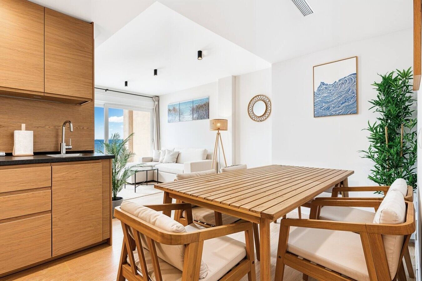 Een moderne keuken met houten kastjes, een eettafel met stoelen, een bank en een vloerlamp.