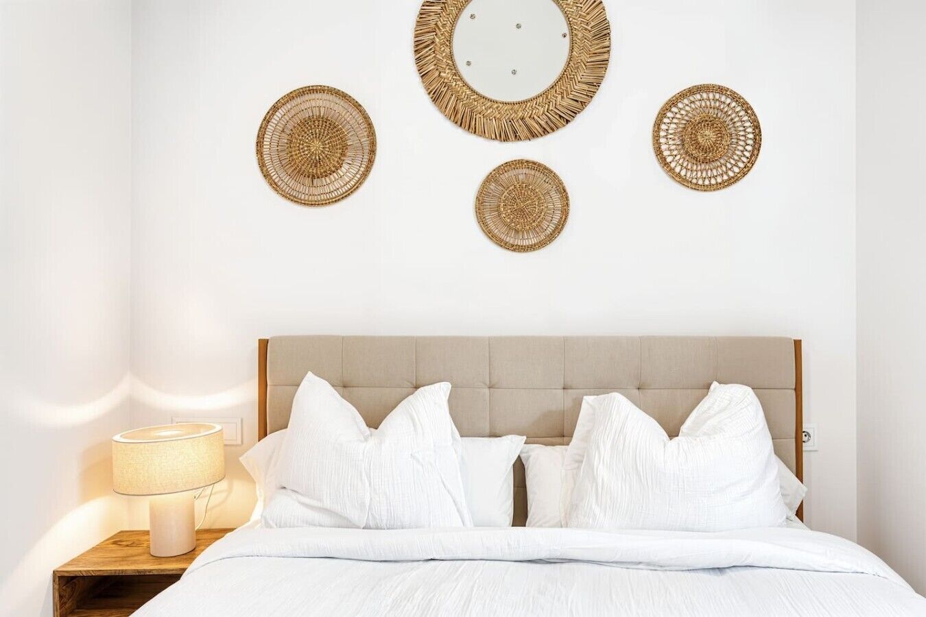 A neatly arranged bedroom with a bed, pillows, a bedside table with a lamp, and wall-mounted decorative items.
