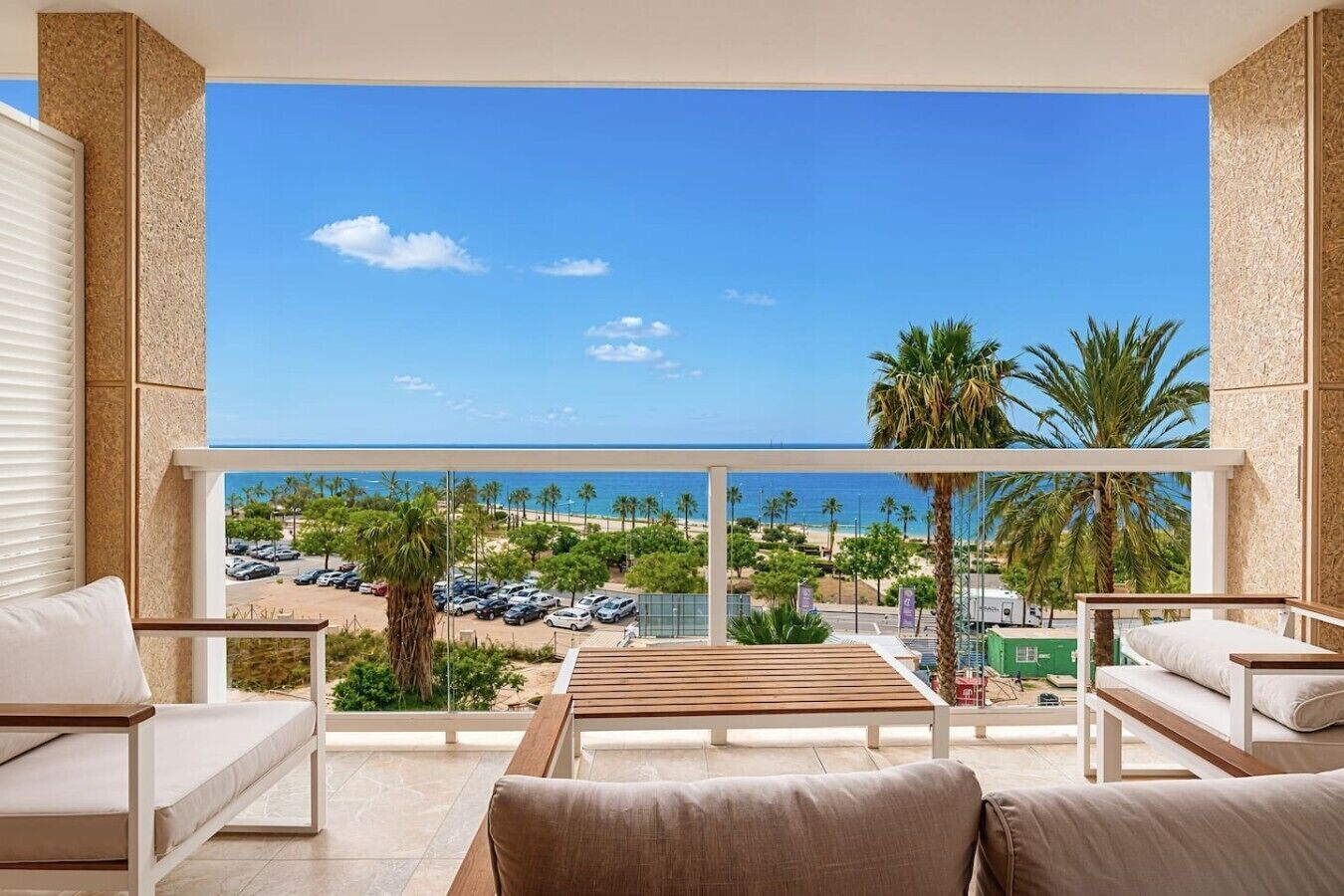 En balkon med udsigt til stranden, en swimmingpool og et spiseområde med udendørs møbler.
