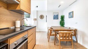 Uma cozinha moderna com armários de madeira, fogão de aço inoxidável e uma área de refeições com mesa e cadeiras de madeira.
