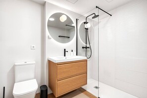 Ein modernes Badezimmer mit Toilette, einem Holzausleger und einer Glaskabine zur Dusche.