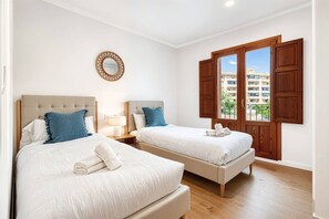 Ein Hotelzimmer mit zwei Betten, einer Holztür, einem Fenster mit Blick und einem an der Wand befestigten Spiegel.