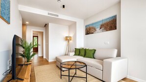 Una sala de estar moderna con un sofá, una mesa de centro, un televisor y un cuadro en la pared.