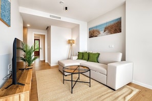 A modern living room with a sofa, coffee table, TV, and a painting on the wall. - Sea View Apartment with Terrace - Breeze (La Vila Joiosa)