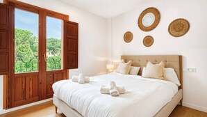Un dormitorio con una cama grande, un armario de madera y una ventana con vistas a zonas verdes.