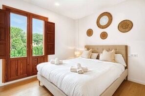 A bedroom with a large bed, wooden wardrobe, and a window with a view of greenery. - Sea View Apartment with Terrace - Breeze (La Vila Joiosa)