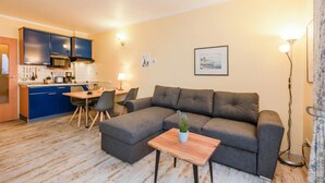 Una sala de estar con un sofá gris, una mesa de centro de madera y un comedor con una mesa y sillas.