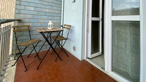 Eine Terrasse mit Tisch, Stühlen und einer Laterne, sowie eine Glastür, die man aufschieben kann.