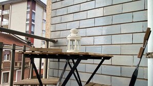 A balcony with a wooden table and chair, a lantern, and a view of a brick building. - Il Bumbunin di Collegno – Free Parking in Central Location (Collegno)